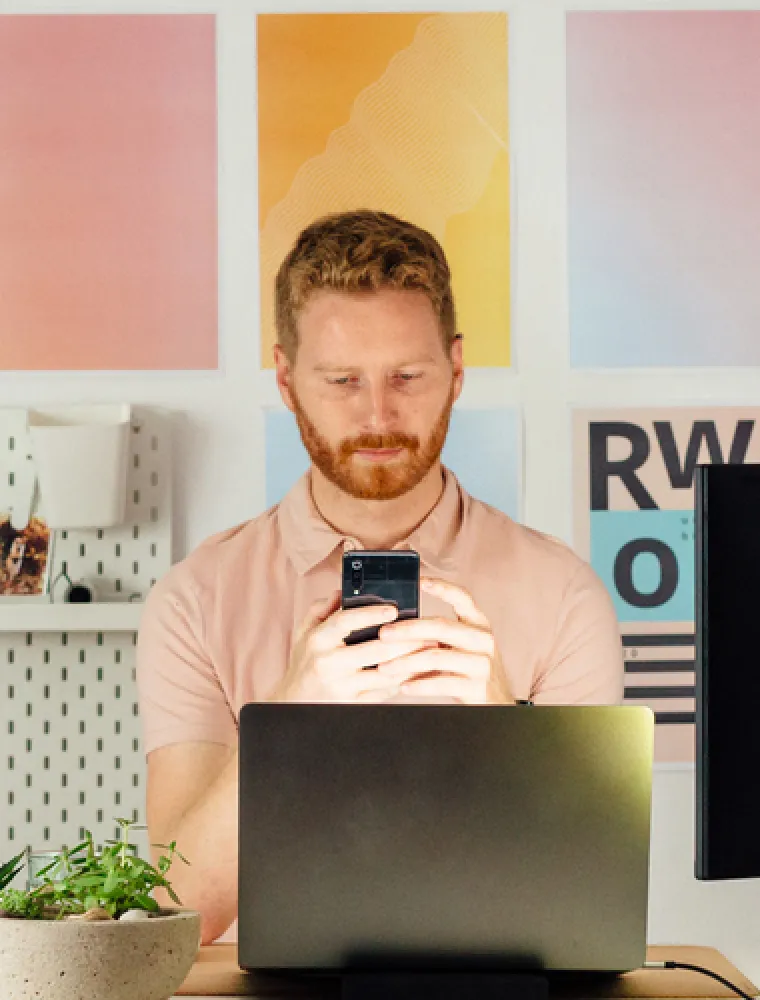 Person checking their phone while working at a laptop